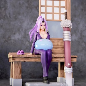 May include: A detailed figurine of a character with long purple hair, wearing a purple outfit, and black boots. The figure is seated on a wooden bench, holding a large blue orb. A decorative sword and a small purple object are also present.