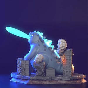 May include: A grey Godzilla-style figurine with a blue dorsal fin and a blue beam coming from its mouth. The figurine is destroying miniature grey buildings, with smoke and flames visible. The base is a textured, rocky surface.