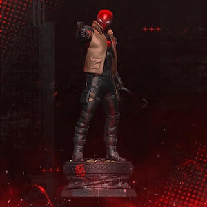 Könnte beinhalten: Eine Red Hood-Figur, die eine Pistole hält, steht auf einem detaillierten Sockel. Die Figur trägt einen roten Helm, eine beige Jacke und schwarze taktische Ausrüstung. Die Statue steht vor einem dunklen, dramatischen Hintergrund.