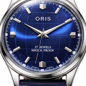 May include: A close-up of a silver-toned wristwatch with a deep blue face. The watch face features the brand name "ORIS", silver hands, and geometric hour markers. The watch has a blue leather band and text that reads "17 JEWELS SHOCK PROOF".
