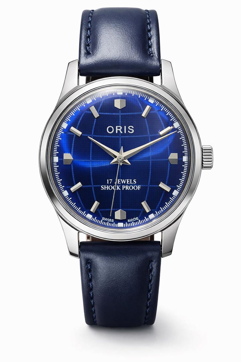 May include: A silver-toned wristwatch with a deep blue face featuring the brand name "ORIS" and the text "17 JEWELS SHOCK PROOF". The watch has a blue leather band and a grid pattern on the watch face.