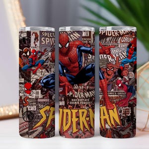 May include: Three stainless steel tumblers with a Spider-Man comic book design. The tumblers display Spider-Man illustrations, comic panels, and text. The colour scheme includes red, blue, yellow, and black. The tumblers are suitable for cold and hot drinks.