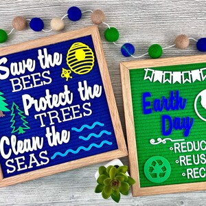May include: Two square felt letter boards with light wood frames. The blue board displays white text reading Save the Bees, Protect the Trees, Clean the Seas with bee, hive, tree, and wave icons. The green board displays Earth Day and recycling text.