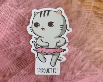 May include: A die-cut sticker featuring a light gray cartoon cat with dark gray stripes on its head, wearing a pink tutu and performing a dance move. The cat has large black eyes and a small mouth. The text "PIROUETTE" is printed in black below the cat.
