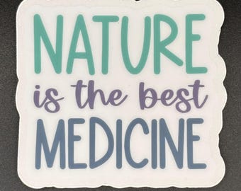 May include: A white sticker with a teal, purple, and blue design. The sticker reads "NATURE is the best MEDICINE" in a whimsical font. The sticker has a white border and is on a dark background.