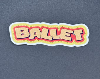 May include: A sticker with the word "BALLET" in a bold, comic book style font. The letters are beige with black outlines, set against a red background with yellow stitching. The sticker has a white border and is on a dark gray surface.
