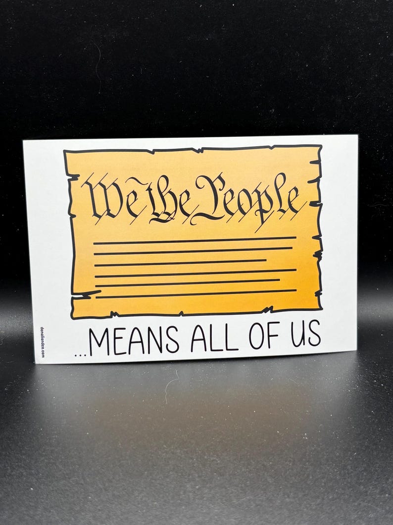 Puede incluir: Una pegatina rectangular con el texto "We the People" en una fuente decorativa, sobre las palabras "...MEANS ALL OF US". El fondo es amarillo con l&iacute;neas horizontales, y el borde es negro.