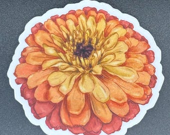 May include: A sticker featuring a watercolor illustration of a zinnia flower. The flower has layers of petals in shades of yellow, orange, and red, with a dark center. The sticker has a white border and is set against a dark background.