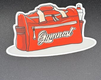 May include: A red duffel bag sticker with the word "Gymnast" in white script. The bag has white accents, a zipper, and a water bottle in the side pocket. The sticker is on a white oval.