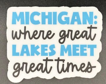 May include: A white die-cut sticker with a black and blue text design that reads: MICHIGAN: where great LAKES MEET great times. The word Michigan and Lakes Meet are in a bold blue sans-serif font, while where great and great times are in black.