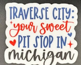May include: A white die-cut sticker featuring the blue text TRAVERSE CITY, red script text your sweet, blue text PIT STOP IN, and black script text michigan. The design includes a red heart, a small blue heart, and two red four-pointed stars.