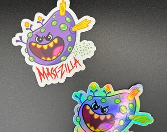 May include: Two stickers featuring a cartoon monster design. One sticker is purple with green spots and the text "MASTZILLA" in red. The other sticker has a holographic finish with the same design and text.