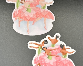 May include: Two stickers featuring illustrations of ballerinas. The ballerinas are depicted in pink petal-like skirts and green tops, with their arms gracefully extended. They are wearing pink pointe shoes and have dark hair.