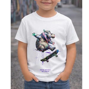Può includere: T-shirt bianca con un'illustrazione colorata di un ippopotamo sullo skateboard. L'ippopotamo è raffigurato con colori vivaci, su uno skateboard. Il testo "MOVE ANYWAY. NO LIMITS." è stampato sotto. La maglietta è indossata da un bambino.
