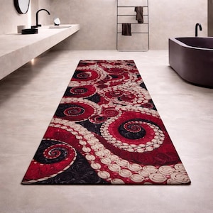 Könnte beinhalten: Ein rechteckiger Badezimmerteppich mit einem auffälligen Tintenfisch-Tentakel-Design. Der Teppich zeigt ein Muster aus roten, schwarzen und cremefarbenen wirbelnden Tentakeln. Der Teppich liegt auf einem hellen Boden in einem modernen Badezimmer.
