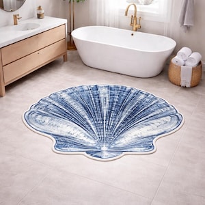 May include: A round bathroom rug shaped like a large seashell, featuring a detailed blue and white gradient print that mimics the radial ridges and texture of a scallop shell, finished with a clean, light-colored bound edge trim.