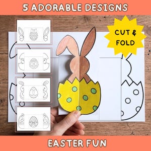 Puede incluir: Una manualidad en papel blanco con cinco diseños de Pascua. La imagen principal muestra un conejito marrón y amarillo saliendo de un huevo roto. El texto incluye "5 ADORABLE DESIGNS", "CUT & FOLD" y "EASTER FUN".