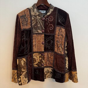 May include: A long-sleeved jacket featuring a patchwork design in shades of brown, gold, and bronze. The garment includes a mandarin collar, a front button closure, and intricate embroidery with beadwork accents. The label reads Indigo Moon.