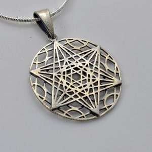 Może przedstawiać: Srebrny naszyjnik z zawieszką w kształcie szczegółowej, misternej gwiazdy. Gwiazda wykonana jest z delikatnego, ażurowego wzoru, tworząc geometryczny i elegancki wygląd.