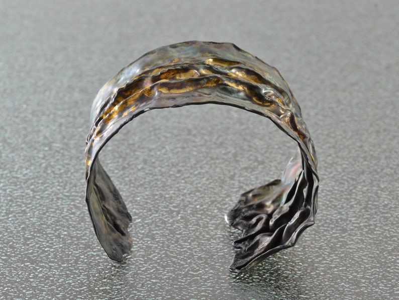 Artistic fold-formed hammered silver-and-gold cuff bracelet.
