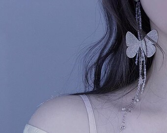 May include: Silver butterfly earrings with dangling chains and small beads. The earrings feature a detailed butterfly design and delicate chain accents. The earrings are a stylish accessory.