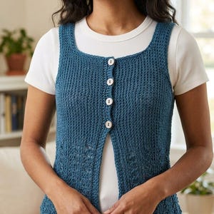 May include: A sleeveless, button-down vest in a teal blue hue. The knitted vest features a square neckline and is fastened with three white buttons. The garment is worn over a white t-shirt. The vest's texture and design are clearly visible.