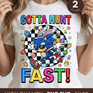 May include: White t-shirt featuring a colorful graphic of Sonic the Hedgehog dressed as a bunny, wearing sunglasses, and running. The text "GOTTA HUNT FAST!" is displayed above and below the character in vibrant colors. Easter-themed design.