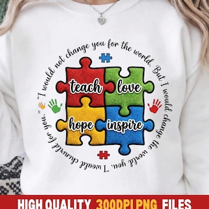 Könnte beinhalten: Weißes Sweatshirt mit einem farbenfrohen Puzzledesign. Die Puzzleteile sind rot, grün, gelb und blau, mit den Wörtern "teach", "love", "hope" und "inspire". Der Text "I would not change you for the world. But I would change the world for you." ist um das Puzzle gedruckt.