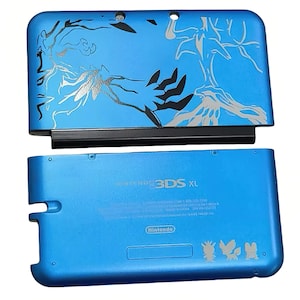 以下が含まれることがあります： 青いニンテンドー3DS XLコンソール。上部カバーには、銀色の木と枝のデザインが施されています。下部カバーは、任天堂のロゴとキャラクターのシルエットが入った無地の青色です。