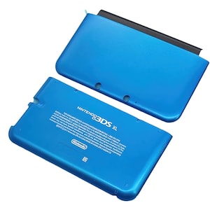 May include: A blue Nintendo 3DS XL console, with the top and bottom halves separated. The bottom half displays the Nintendo logo and product information. The top half has a black hinge. The console is a vibrant blue color.