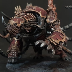 May include: A detailed miniature figure of a monstrous creature, painted in shades of red, bronze, and gray. The figure has a horned head, sharp claws, and multiple segmented appendages, suggesting a fantasy or sci-fi theme.