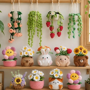 Könnte beinhalten: Eine Sammlung gehäkelter Objekte, darunter vier hängende Pflanzenkörbe mit Ranken und Erdbeeren sowie neun Topfpflanzenfiguren mit Blumen, einem Hasen, einem Schwein und Bären in verschiedenen Farben wie Rosa, Braun und Weiß.