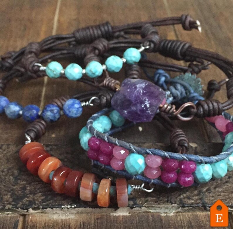 K&ouml;nnte beinhalten: Ein Set aus f&uuml;nf Lederarmb&auml;ndern mit verschiedenen Edelsteinperlen. Die Armb&auml;nder haben T&uuml;rkis-, Amethyst-, Karneol- und Lapislazuli-Perlen. Das Leder ist braun und die Perlen sind auf silbernem Draht aufgef&auml;delt.