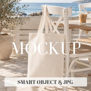 Puede incluir: Una bolsa de tela de color blanco roto con dos asas largas colgada del respaldo de una silla de madera blanca. La imagen muestra el texto blanco MOCKUP en el centro y SMART OBJECT & JPG en un recuadro blanco en la parte inferior.