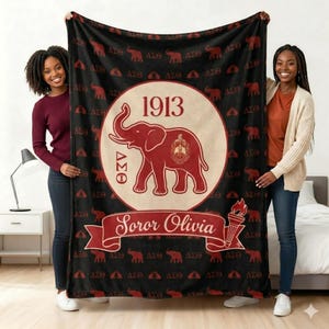 May include: Black blanket with a repeating pattern of red elephants and Greek letters. A large central emblem features a red elephant, the year 1913, and the words "Soror Olivia." A torch graphic is also present.