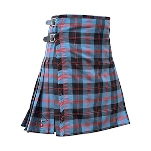 Może przedstawiać: Niebiesko-czarno-czerwona krata kilt ze skórzanymi paskami i klamrami. Kilt ma plisowany design i postrzępione krawędzie. Kilt ma logo z napisem "kilts fit".