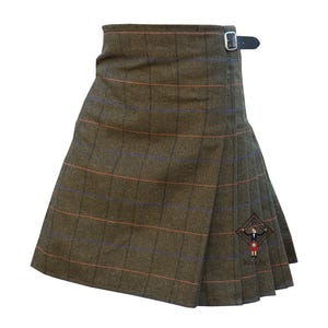 May include: A brown kilt with a plaid pattern featuring orange and blue lines. The kilt has a wrap-around design with a leather strap and buckle closure. The garment is made of a textured fabric.