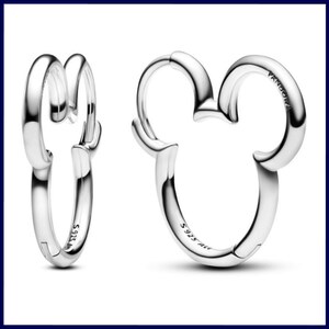 Op de afbeelding: Een paar zilveren oorringen. E&eacute;n oorring is een klassiek ontwerp, terwijl de andere de vorm heeft van Mickey Mouses hoofd. De oorbellen zijn gemarkeerd met "S925 ALE" en het Pandora-logo. De oorbellen zijn gemaakt van glanzend, reflecterend metaal.