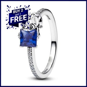 May include: A silver ring with a cartoon character and a square, deep blue gemstone. The ring band is decorated with small, clear stones. The text "BUY 2 get 1 FREE" is in a blue and white banner. The ring is marked with "Disney" and "S925".