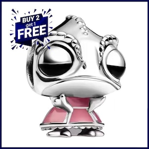 May include: A silver-toned charm bead shaped like a stylized chameleon with large black eyes and a pink enameled skirt. The charm features a textured head and a flared dress design. A blue graphic overlay in the corner displays the text BUY 2 get 1 FREE.