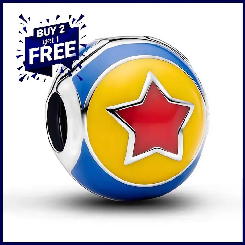 May include: A spherical charm bead featuring a yellow circular center with a red star, surrounded by a blue border and silver metal edges. The charm includes a dark blue graphic overlay in the upper left corner with the text BUY 2 get 1 FREE.