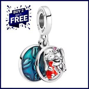May include: A silver charm featuring a cartoon illustration of two characters hugging, with a blue and teal design on the reverse. The charm has a loop for attaching to a bracelet or necklace. The text "BUY 2 get 1 FREE" is in the upper left corner.