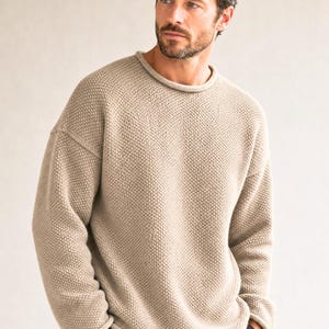 Può includere: Un maglione beige a maniche lunghe con un motivo a maglia testurizzato, scollo rotondo con bordo arrotolato e spalle scese. Il capo presenta una vestibilità rilassata con orlo dritto e maniche lunghe che arrivano ai polsi.