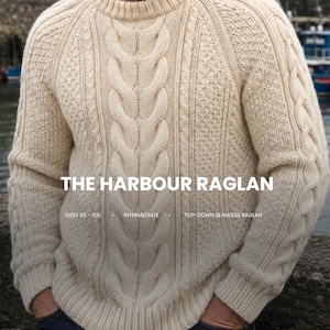 Peut inclure: Un pull en tricot torsadé blanc cassé avec un col rond et des manches raglan. Le texte sur l'image indique : THE HARBOUR RAGLAN, SIZES XS - 5XL, INTERMEDIATE, TOP-DOWN SEAMLESS RAGLAN. Le pull présente un motif texturé avec des torsades verticales.