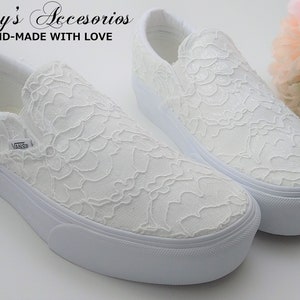 Könnte beinhalten: Ein Paar weiße Slip-on-Sneaker mit Plateau und einer Spitzen-Überlagerung. Die Schuhe sind aus einem weichen, bequemen Material gefertigt und haben ein klassisches, zeitloses Design. "Rossy's Accesorios HAND-MADE WITH LOVE" ist oben im Bild gedruckt.