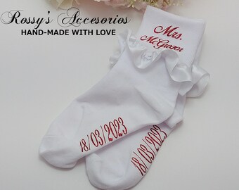 Puede incluir: Calcetines blancos con ribete de volantes y bordado rojo que dice "Mrs. McGregor" y "18/03/2023".