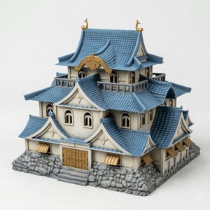 May include: A detailed miniature Japanese castle model. The structure features a blue roof, white walls, and gold accents. The base is made of gray stone. The model has multiple levels, windows, and decorative elements.