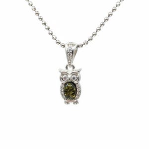May include: Silver owl pendant necklace with a green oval gemstone center and clear accent stones. The owl pendant is suspended from a silver ball chain. The necklace is displayed against a white background.