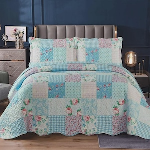 May include: A patchwork quilt and two pillowcases in shades of blue, white, and pink. The quilt features floral prints, polka dots, and gingham checks. The bedding set is displayed on a bed with a grey headboard.