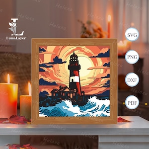 Puede incluir: Una impresión artística enmarcada representa una escena de faro. El faro, con rayas rojas y blancas, se alza sobre una puesta de sol con tonos naranja, amarillo y azul. La obra de arte está enmarcada en un marco de madera e incluye el texto "SVG, PNG, DXF, PDF".